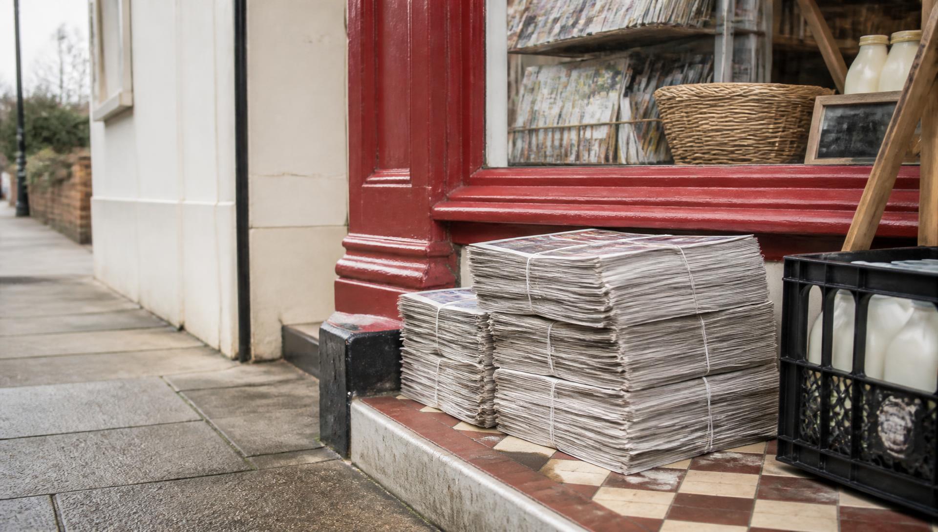 Bundles of morning newspapers on the doorstep of a British corner shop